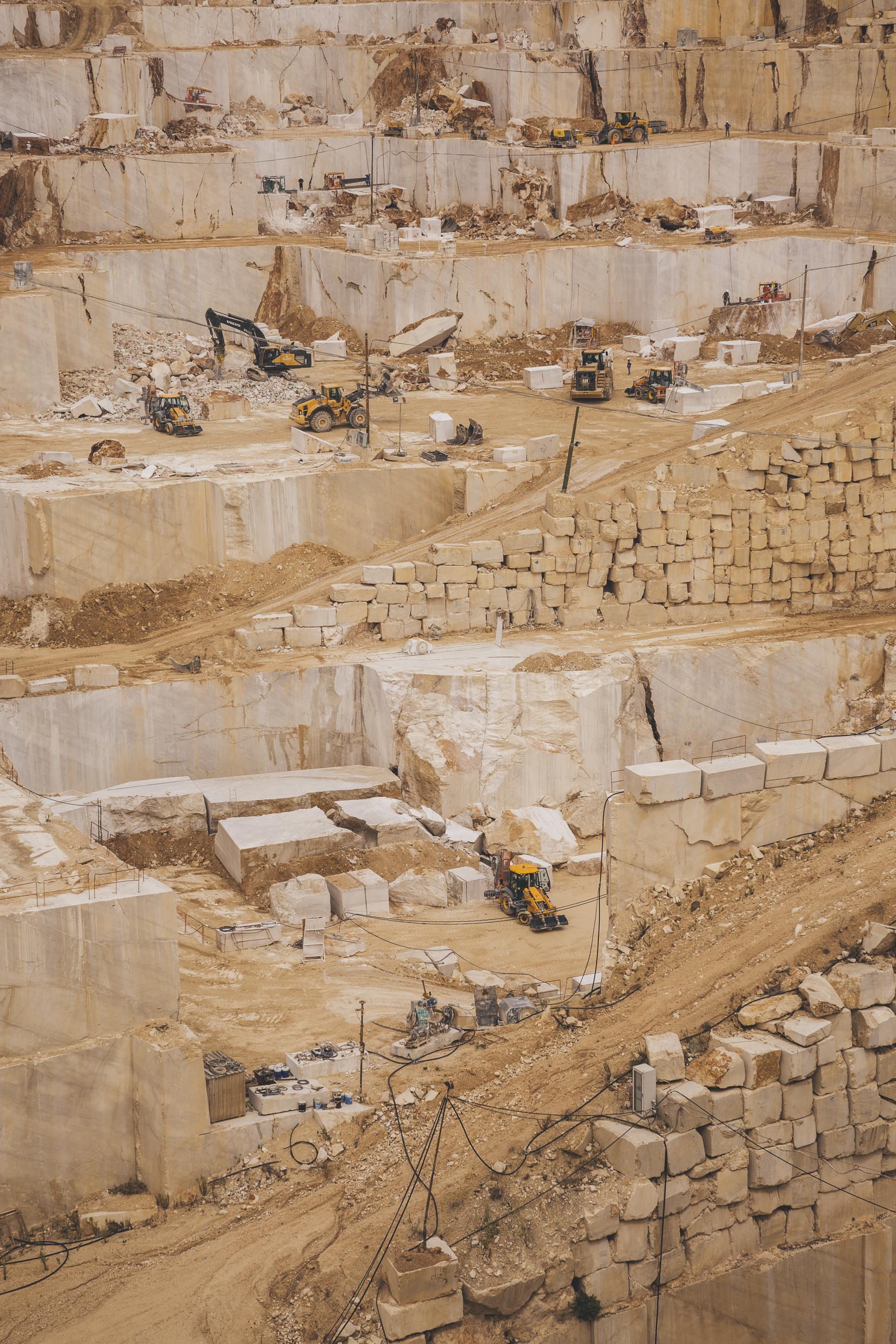 Ein großer Steinbruch mit Terrassen, schweren Maschinen und Geräten, die auf verschiedenen Ebenen arbeiten, fängt die Essenz industrieller Macht ein – eine Szene, die der Business-Fotografie würdig ist.